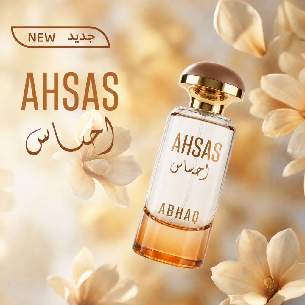 ABHAQ Ahsas perfume bottle with a white frosted body, gold cap, and Arabic calligraphy label, surrounded by soft cream-colored flowers on a warm golden background.